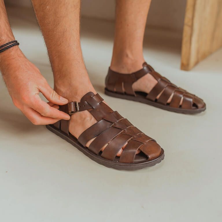 Close-up bruine leren heren sandalen met hand aan de gesp