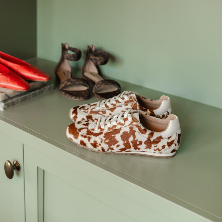 platte schoen met koeienprint op een geschilderde kast