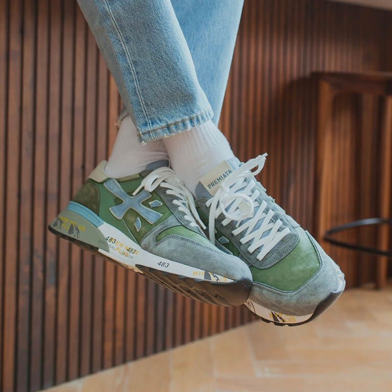 Gekruiste onderbenen met Premiata blauw/groene Premiata sneakers voor in de zomer