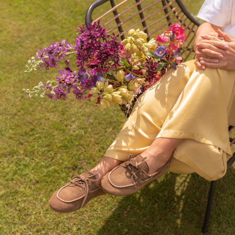 vrouw op het gras zittend op een stoel met bloemen