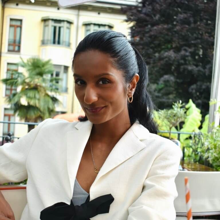 Danique Sprokholt met witte blazer met zwarte strik voor geel gebouw