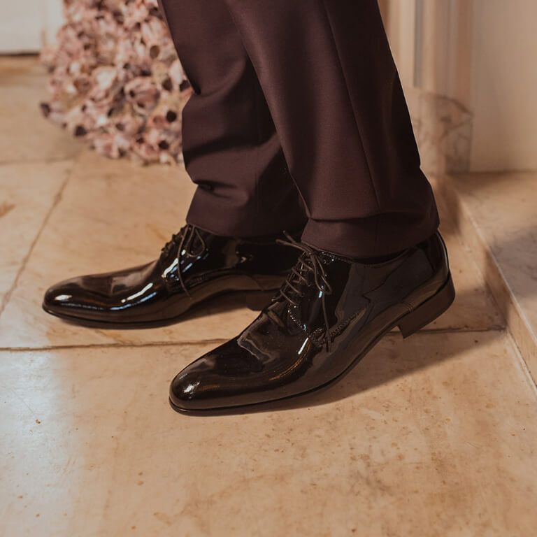 Zwarte lakleren veterschoenen onder zwarte pantalon