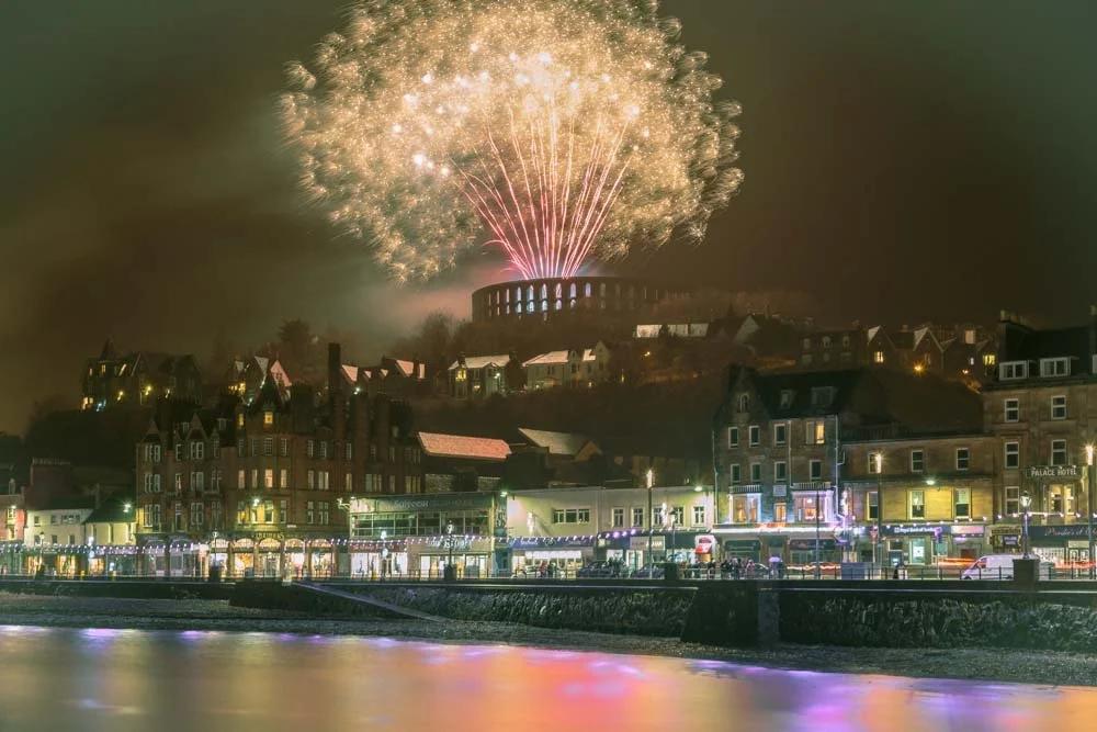 Image of Oban at night during the winter festival as some fireworks go off