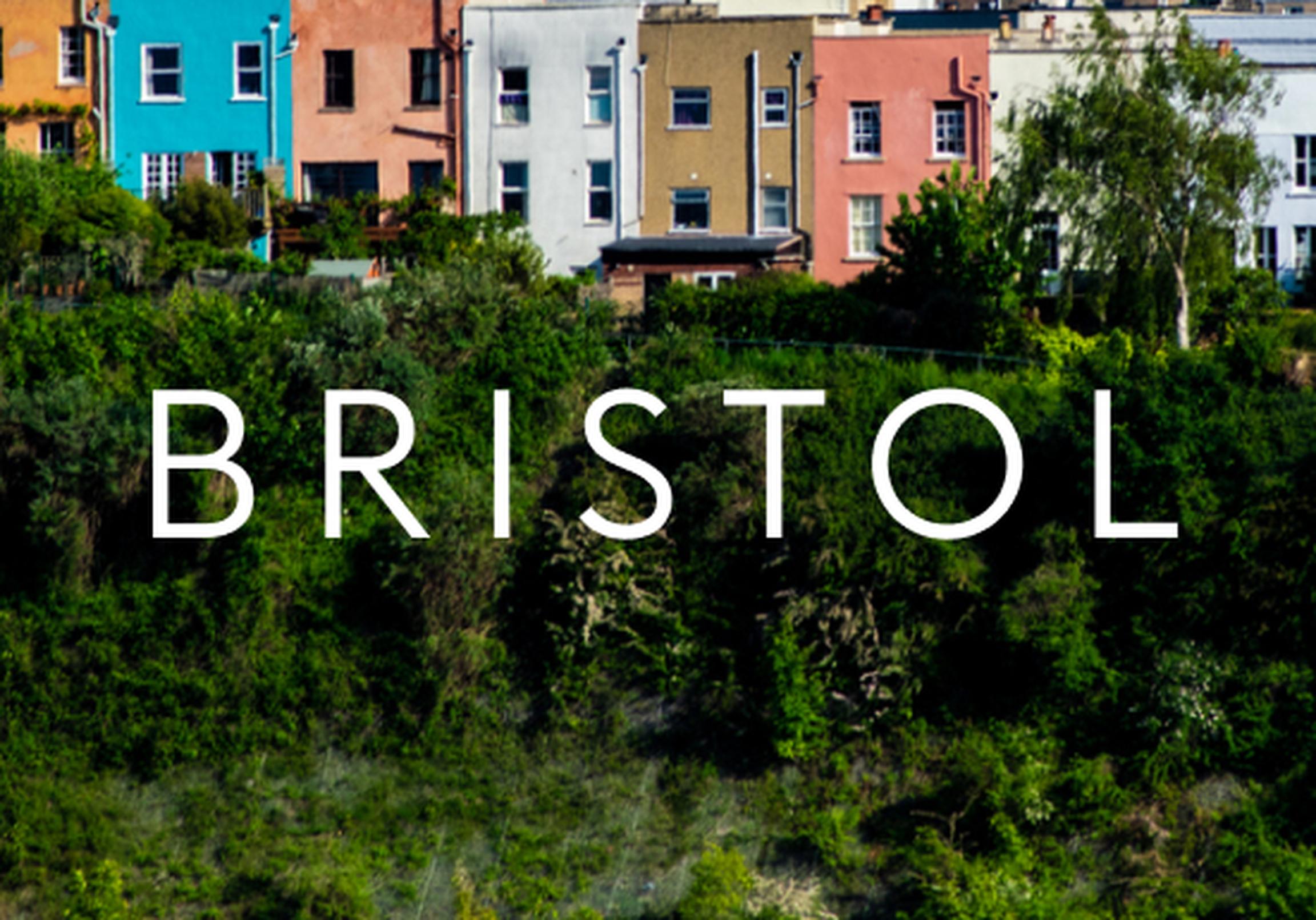 Colorful houses on a hillside in Bristol, with lush greenery in the foreground and the word "BRISTOL" overlaying the image.