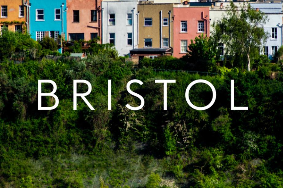 Colorful houses on a hillside in Bristol, with lush greenery in the foreground and the word "BRISTOL" overlaying the image.