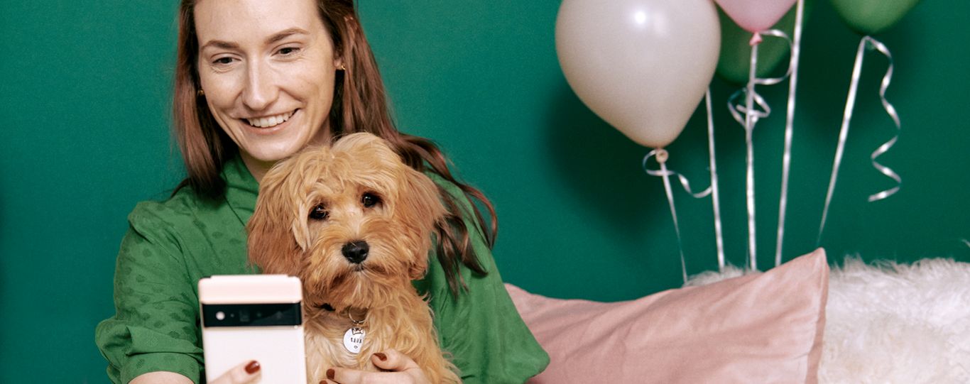Woman taking a picture of a dog sat on her lap