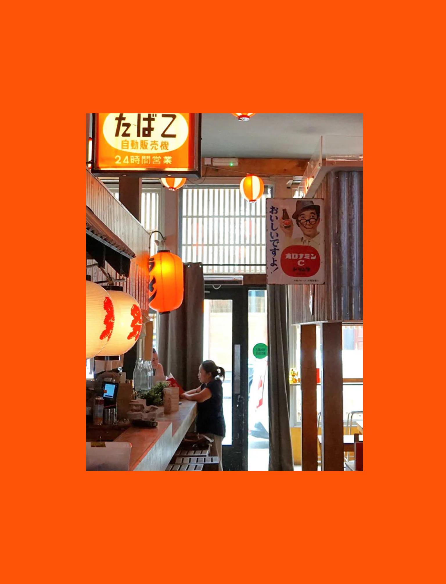 Japanese-themed restaurant interior with warm lighting, paper lanterns, and traditional  signs.