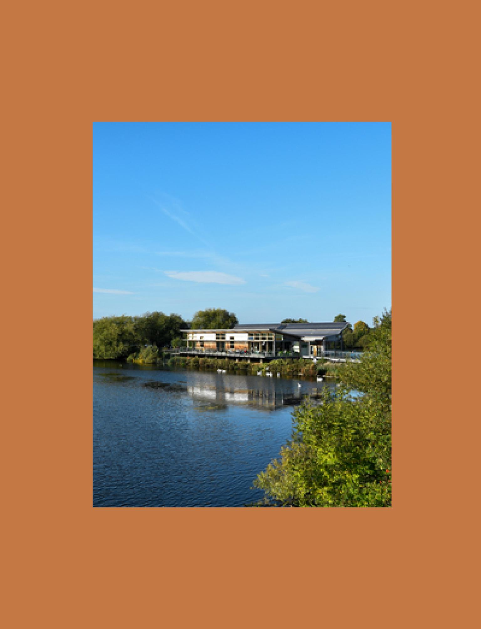 Modern visitor centre surrounded by a serene lake and lush greenery.