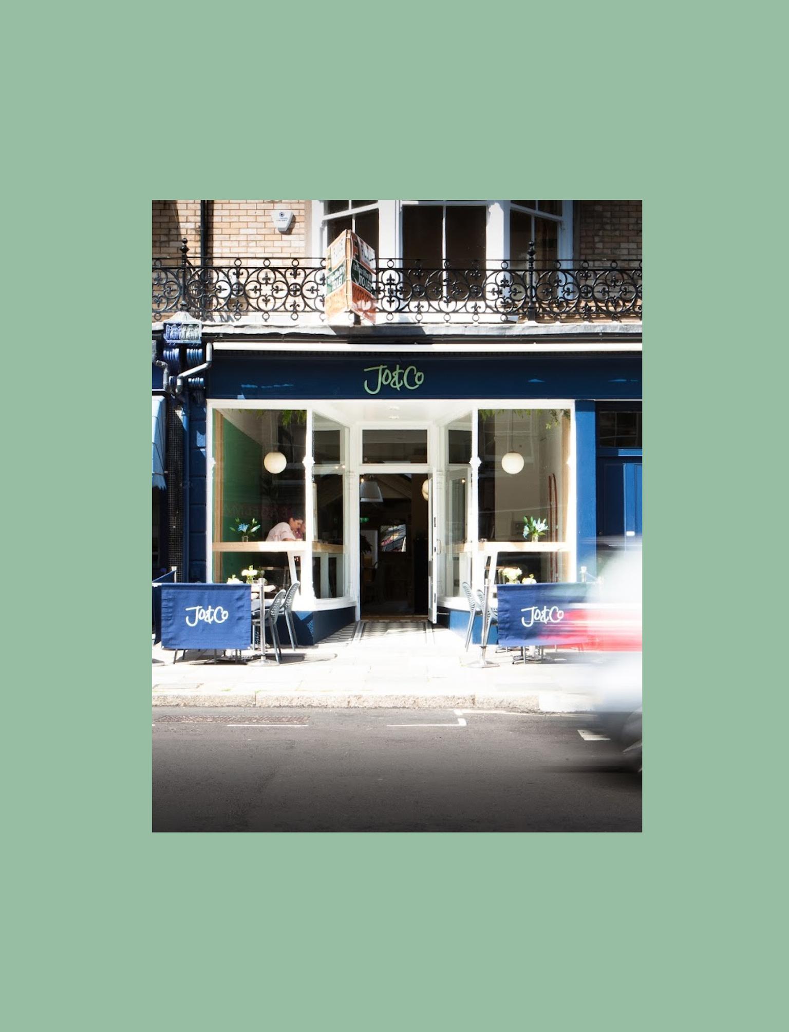 Restaurant front with a blue sign and chairs and tables outside
