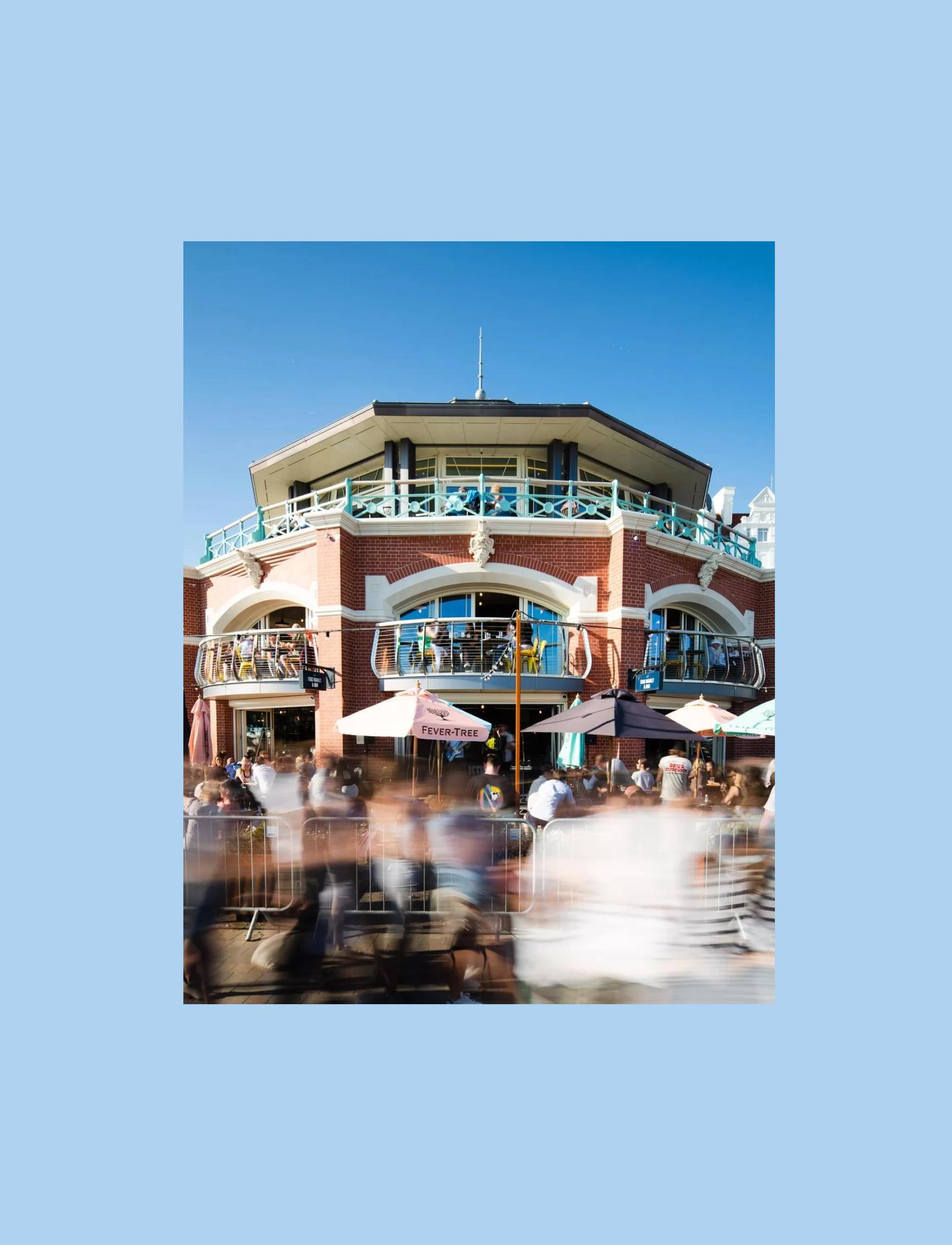 A busy rounded brick seafront building with three balconies and a terrace.