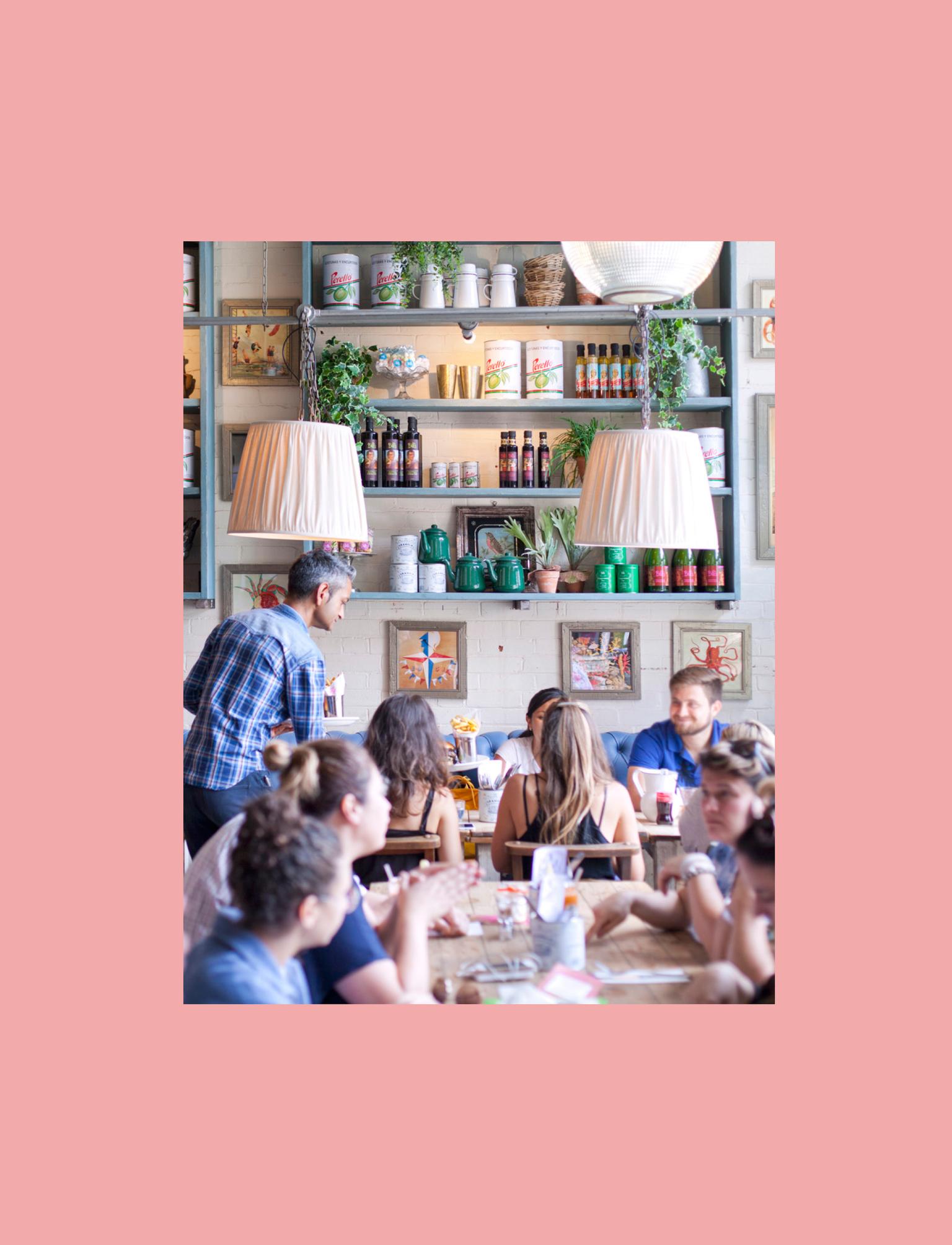 Man serving food to customers in bright restaurant.