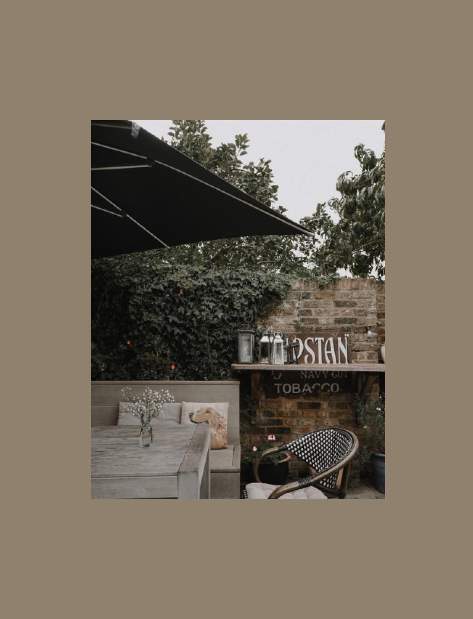 Pub patio with vintage decor, a dog cushion, and greenery.