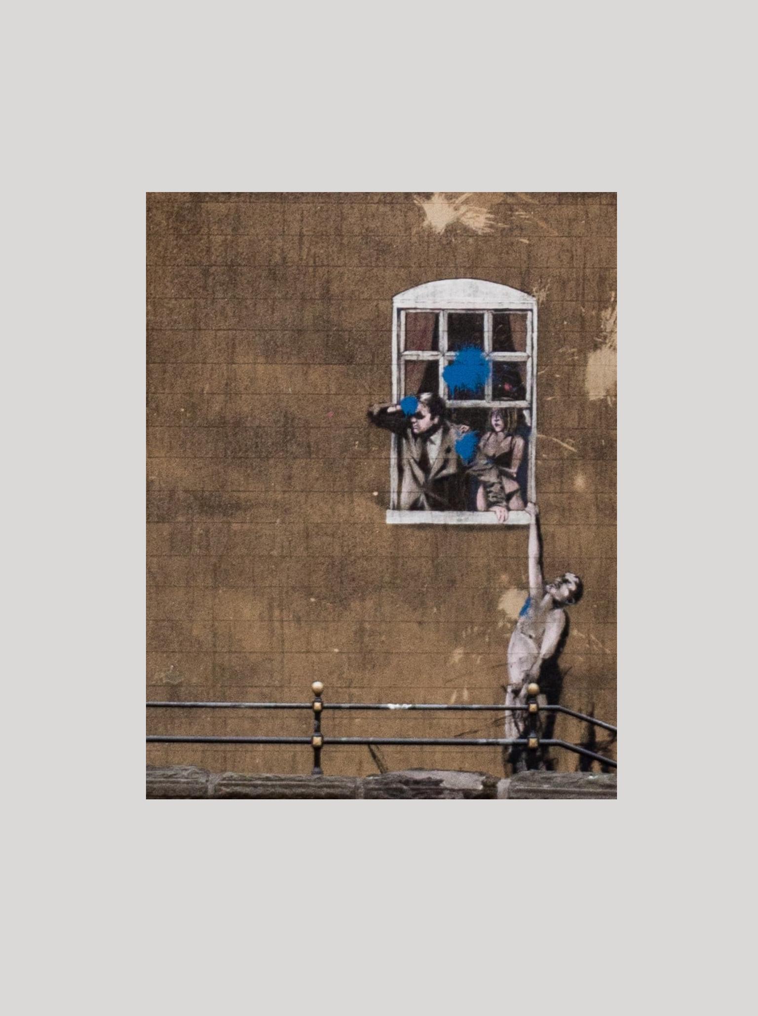 Bansky street art of man holding onto window ledge