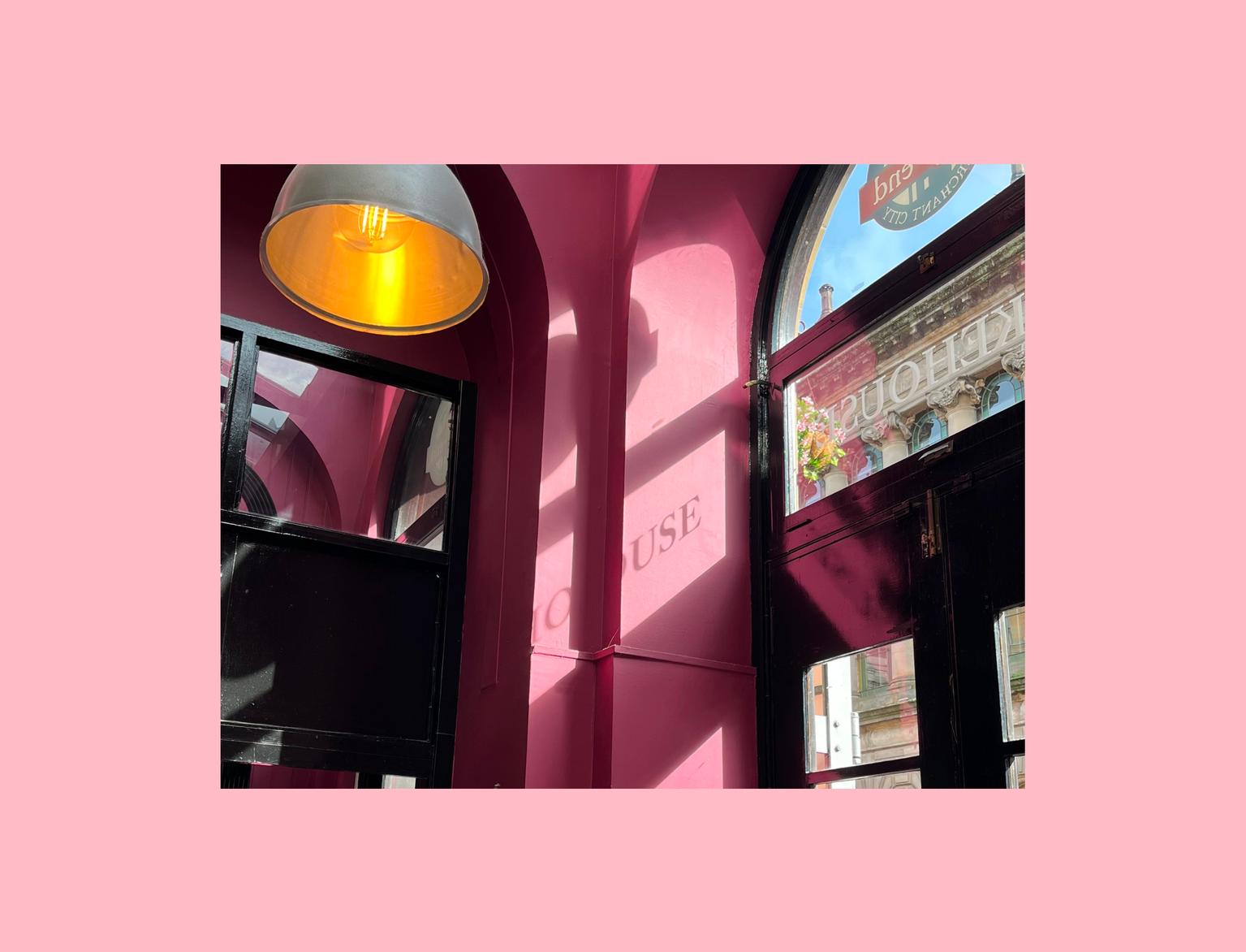 Vibrant pink café interior basking in sunlight, highlighting a charming display and cosy ambiance.