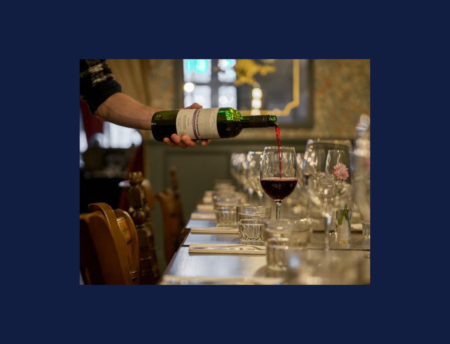 bottle of red win being poured into a glass