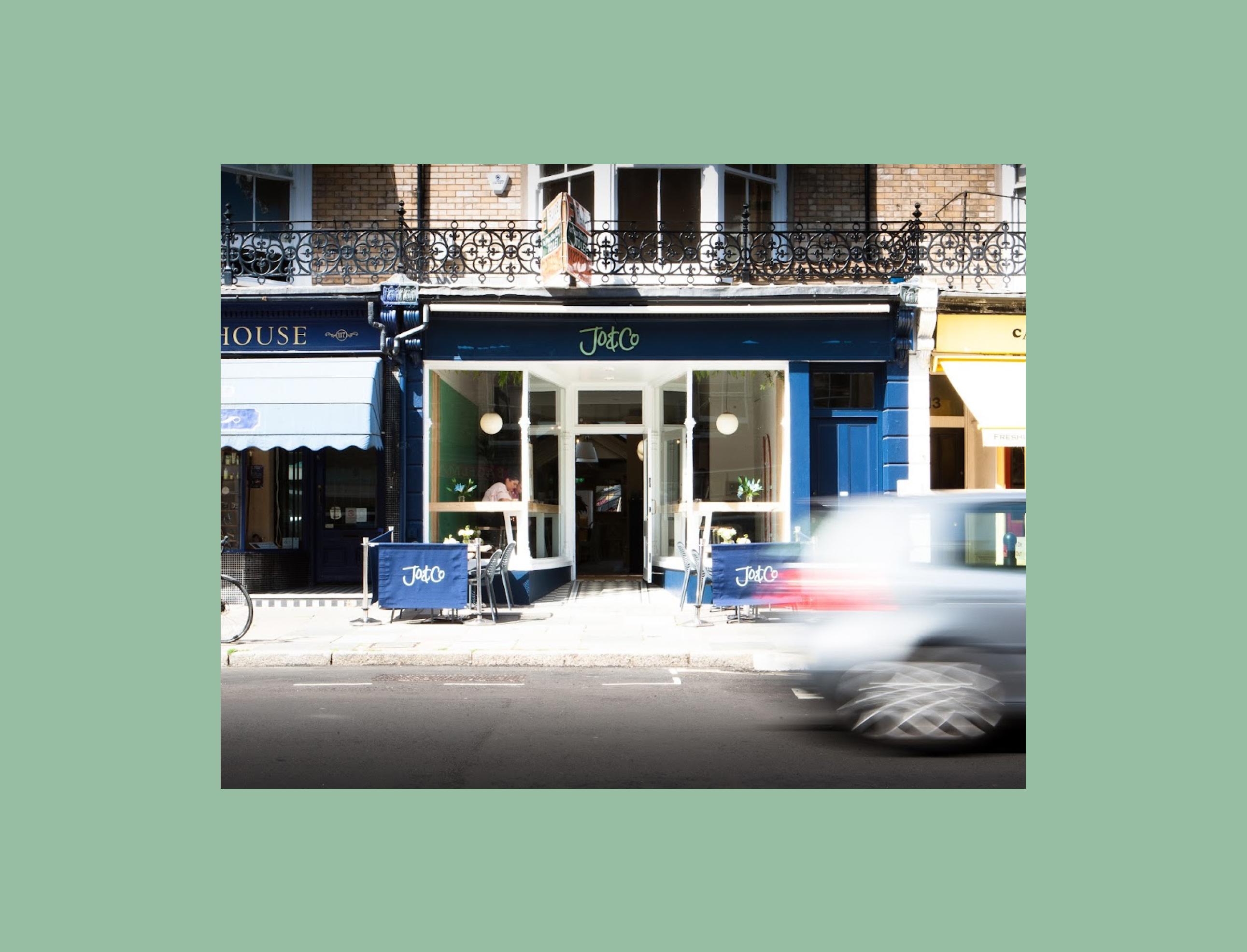 Restaurant front with a blue sign and chairs and tables outside