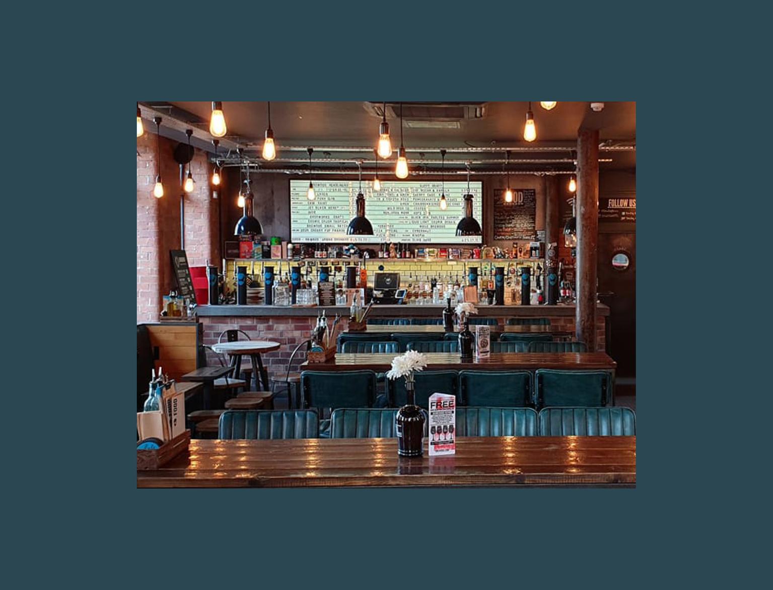 Interior of a cosy bar with exposed brick walls and industrial-style lighting.