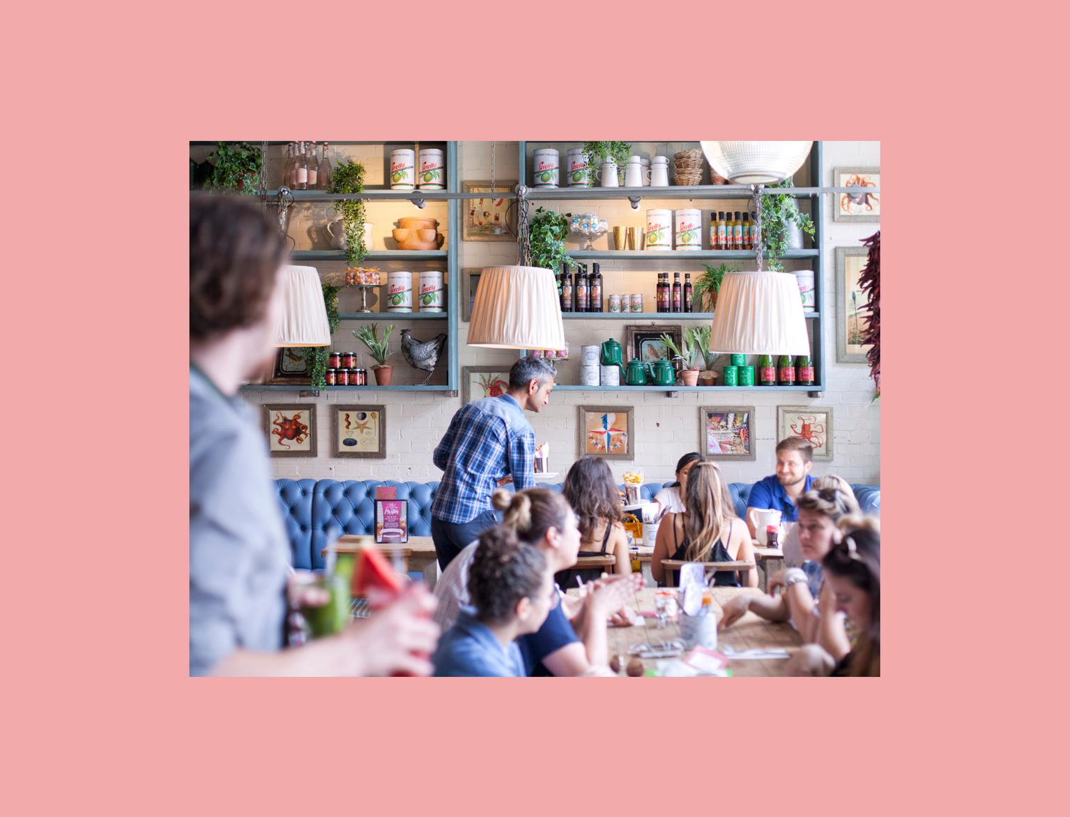 Man serving food to customers in bright restaurant.