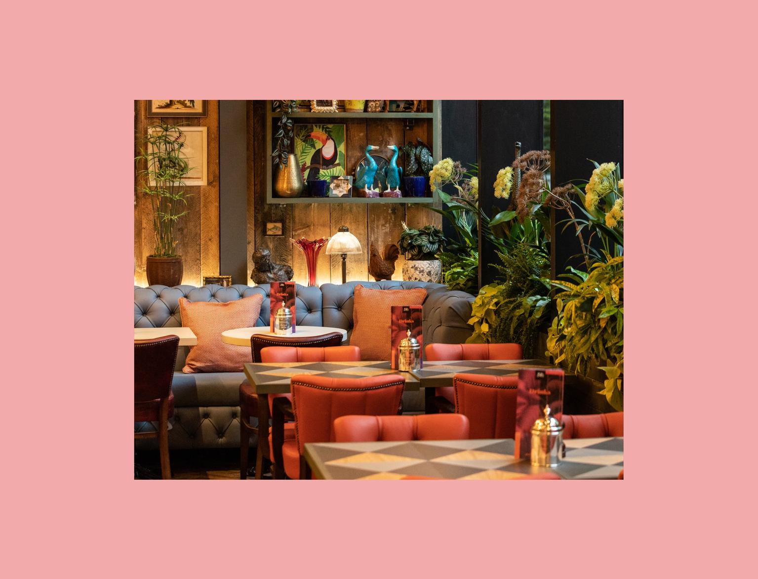 Restaurant with red leather chairs and plants for decoration.