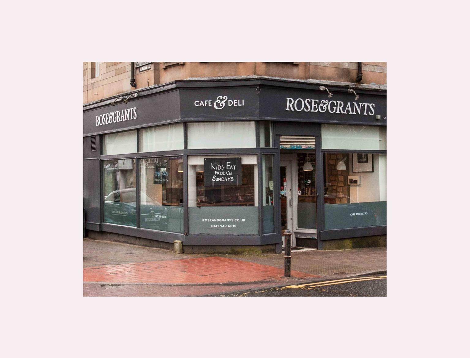 Rose &amp; Grants Cafe &amp; Deli corner facade with large windows and signage, under a cloudy sky.