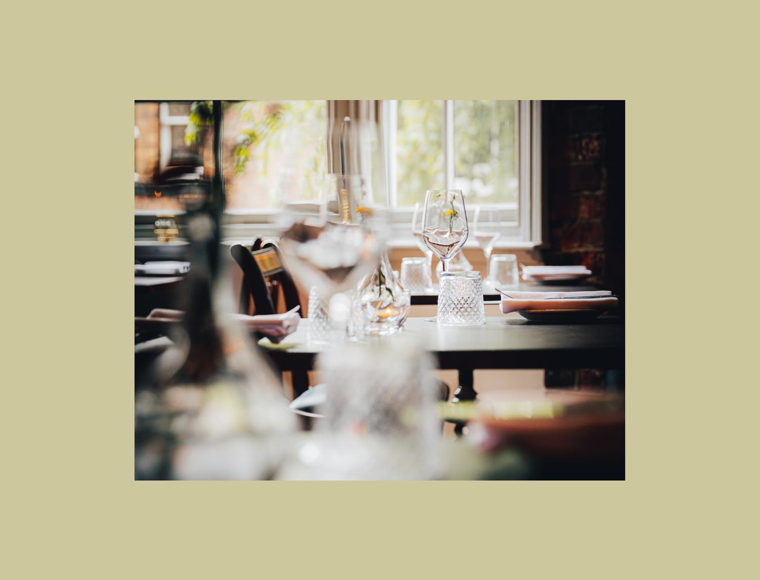 Elegant restaurant setting with sunlight streaming through windows onto neatly arranged tables.