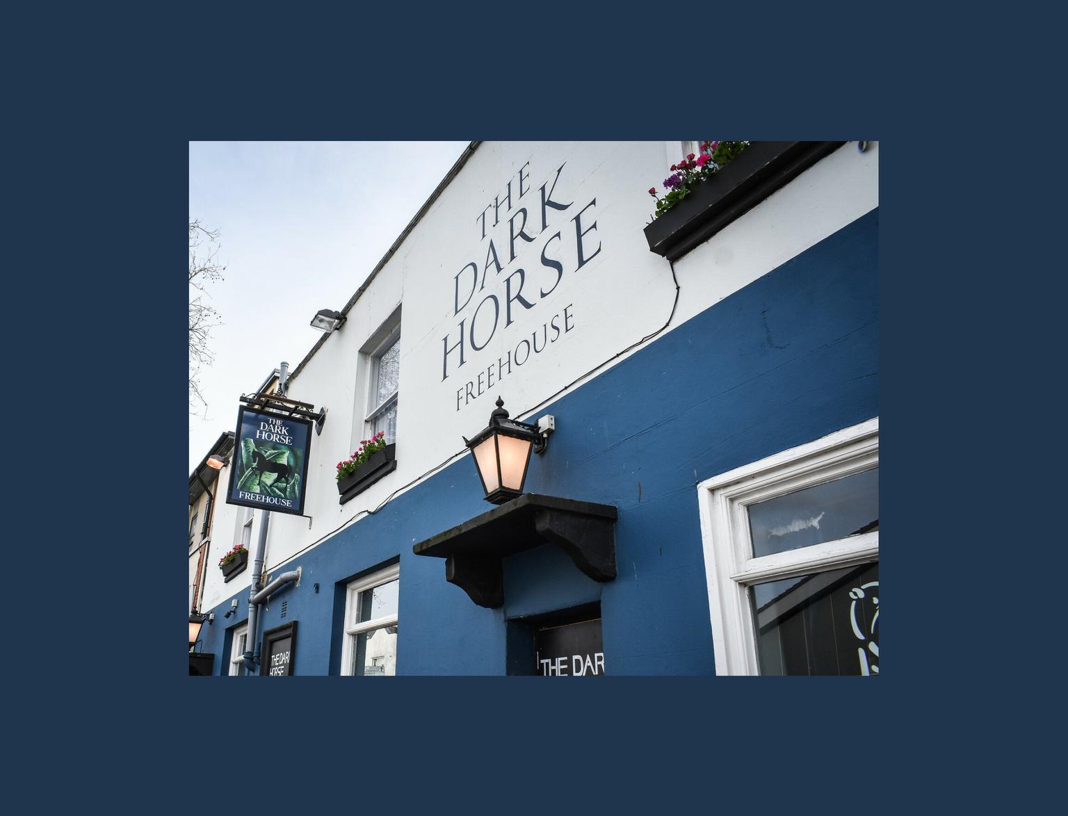 A blue and white painted front of a pub, with a black lantern hanging on the wall