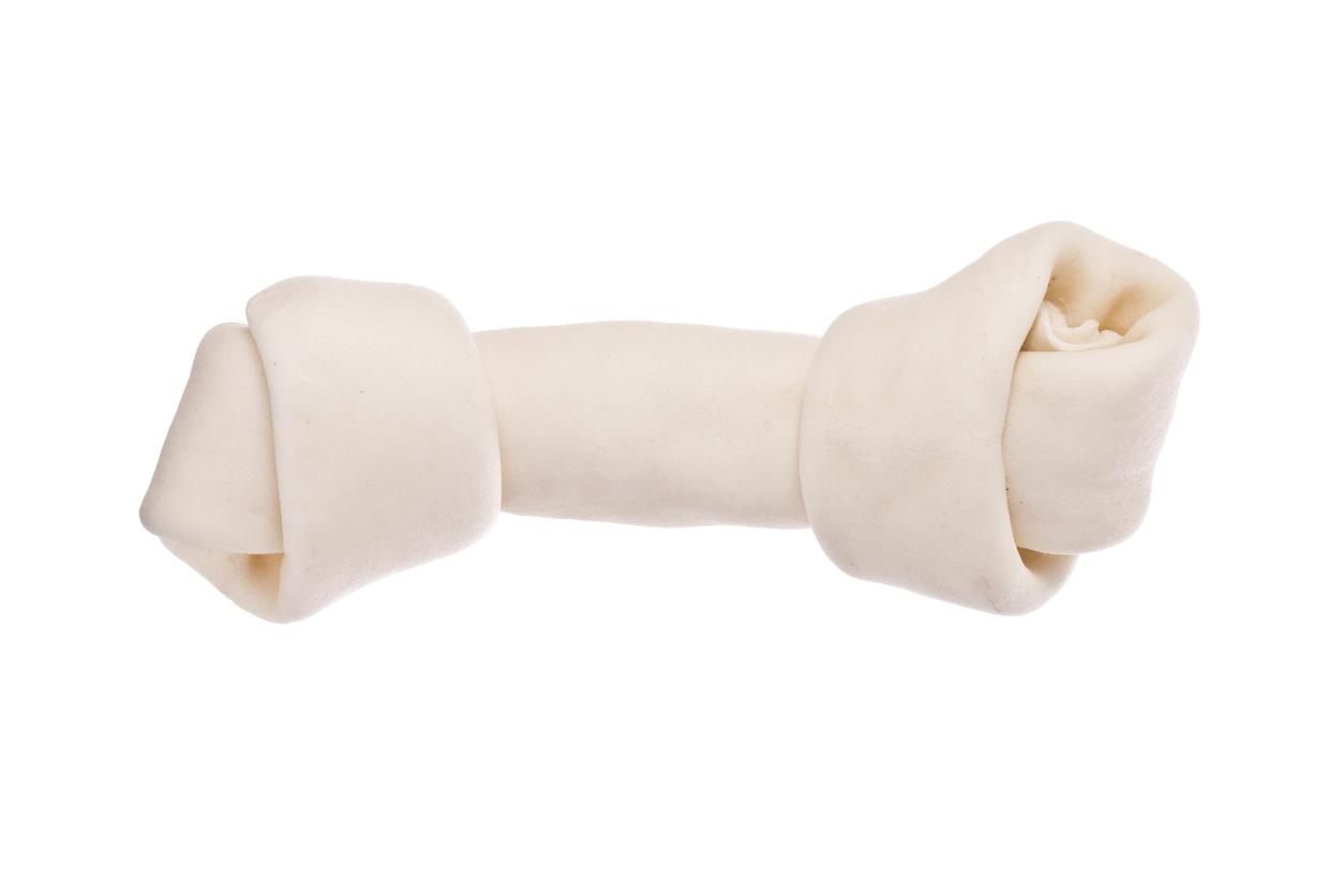 Close-up of a rawhide treat in the shape of a bone on a white background