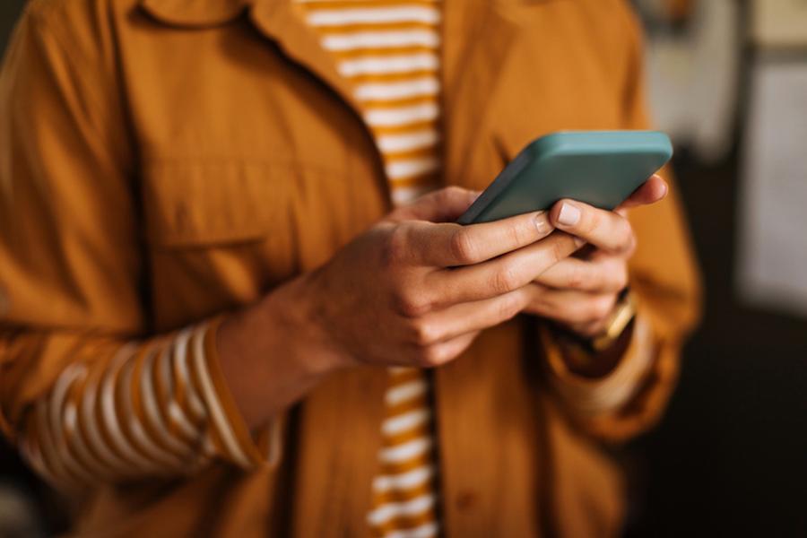 Person in a brown jacket using a smartphone.