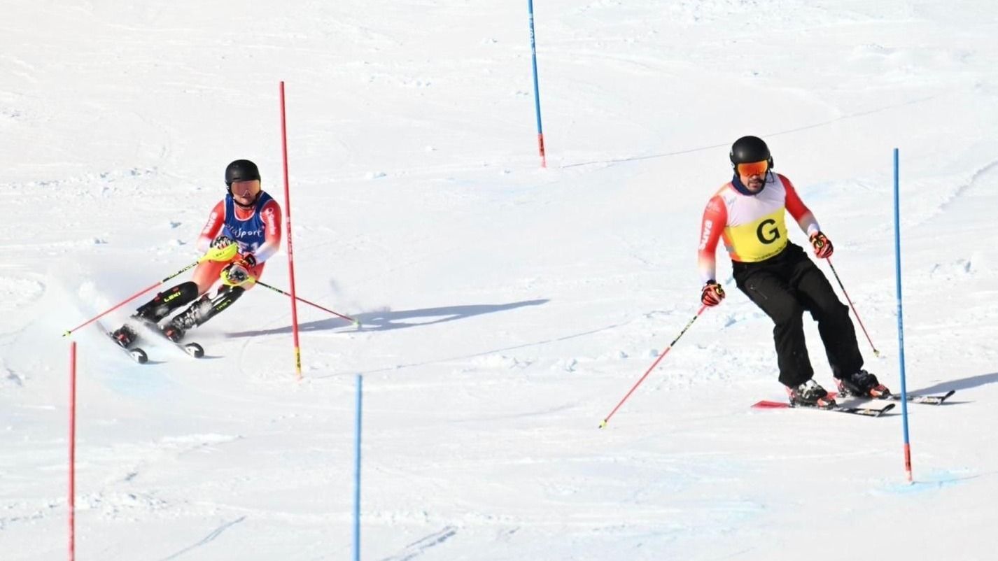 Marc Bleiker fährt Slalom auf der Piste. Vor ihm fährt der Guide. Er gibt Marc Bleiker die Richtungsangaben per Funk durch.