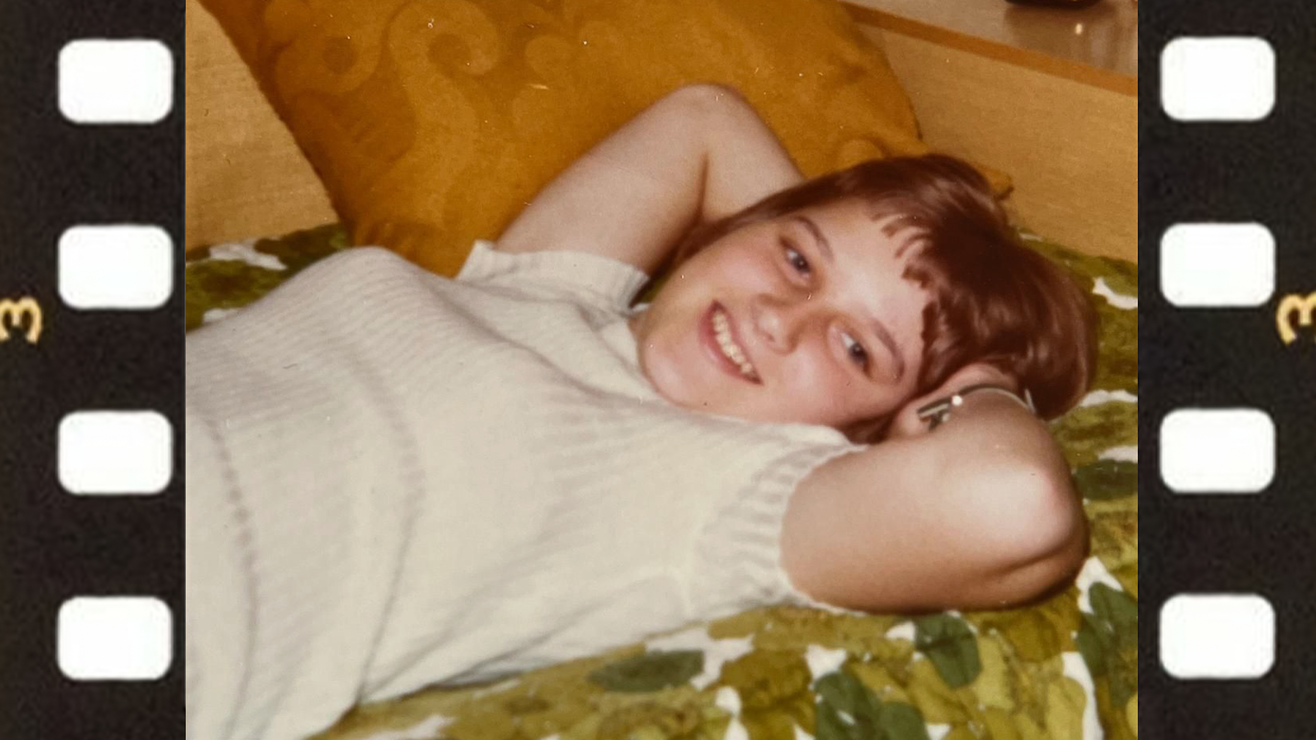 Dora Bigler als Kind. Sie liegt auf dem Sofa und lächelt in die Kamera.