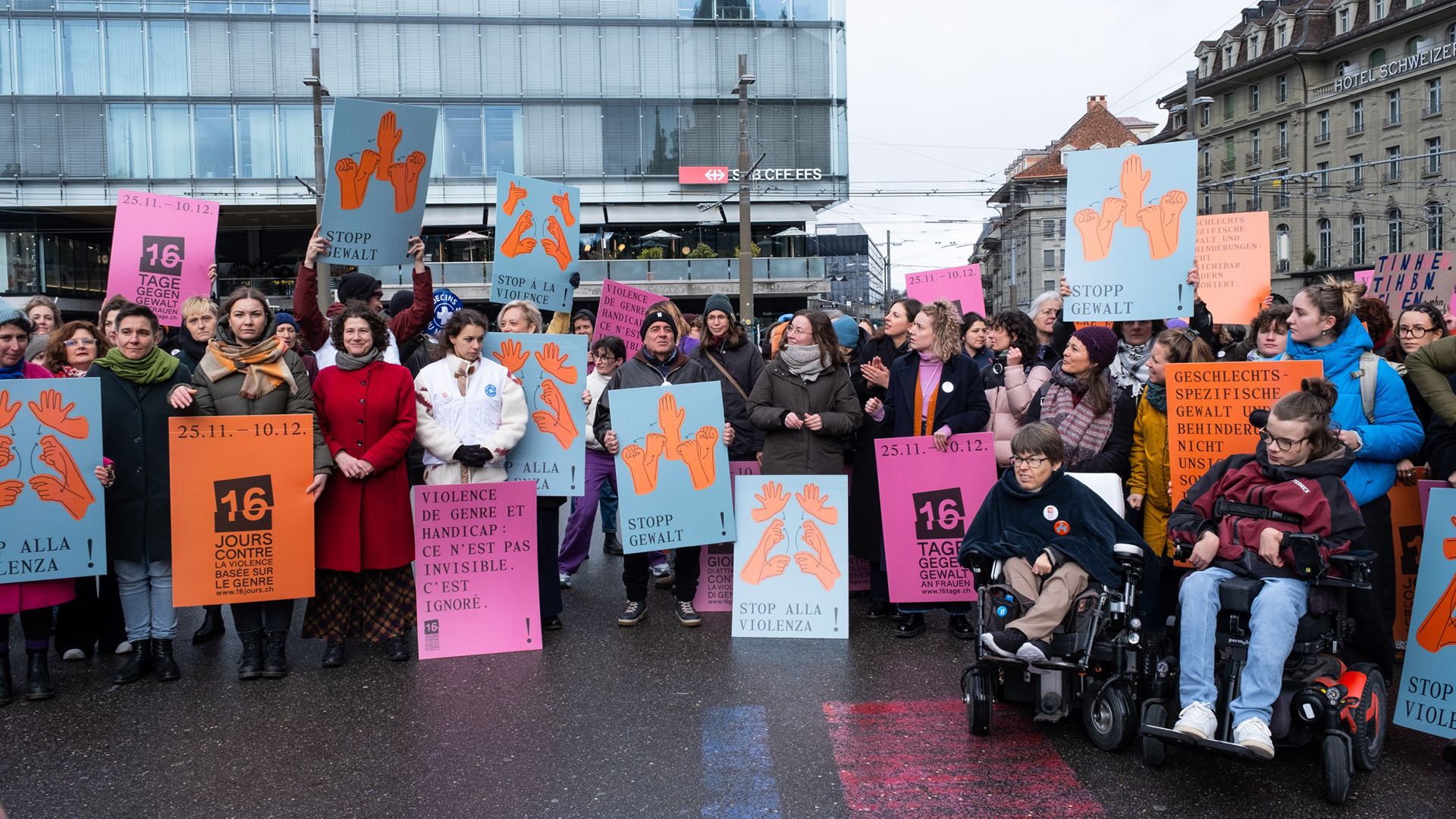 Auftaktveranstaltung der internationalen Kampagne ‚16 Tage gegen Gewalt an Frauen‘ auf dem Bahnhofplatz in Bern: Menschen versammeln sich mit Bannern und Informationsmaterial, um auf Gewalt gegen Frauen und queere Personen mit Behinderungen aufmerksam zu machen