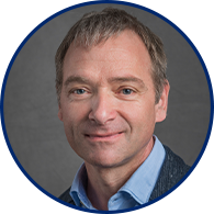 Dr. med. Markus Schlemmer lächelt in die Kamera. Er hat blaue Augen, graue kurze Haare und trägt ein hellblaues Hemd mit einem Jacket.