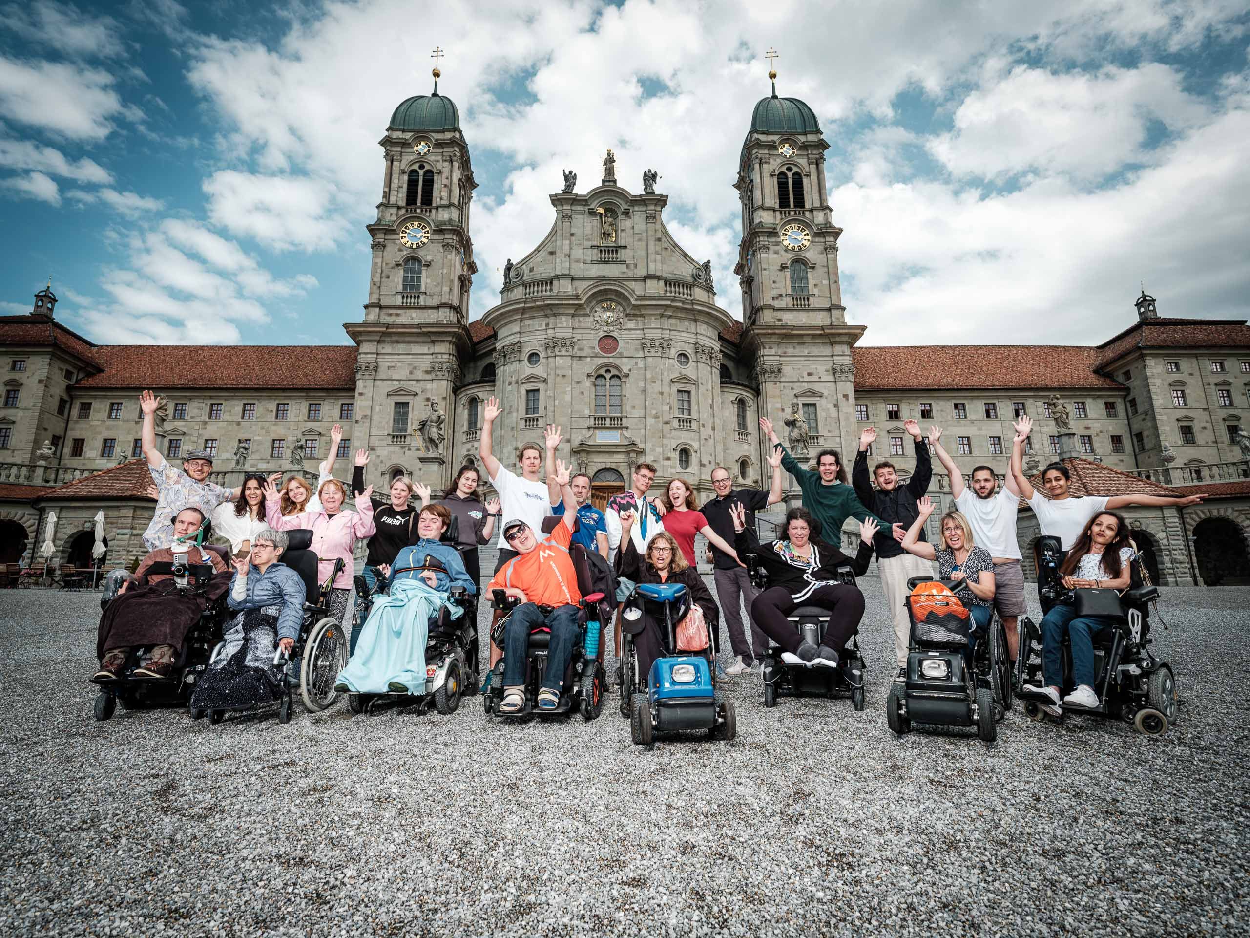 Teilnehmer:innen und Betreuer:innen des Lagers der SMG mit dem Kloster Einsiedeln im Hintergrund. Bildquelle: Boostr. Gruppenfoto der Lagerteilnehmer:innen