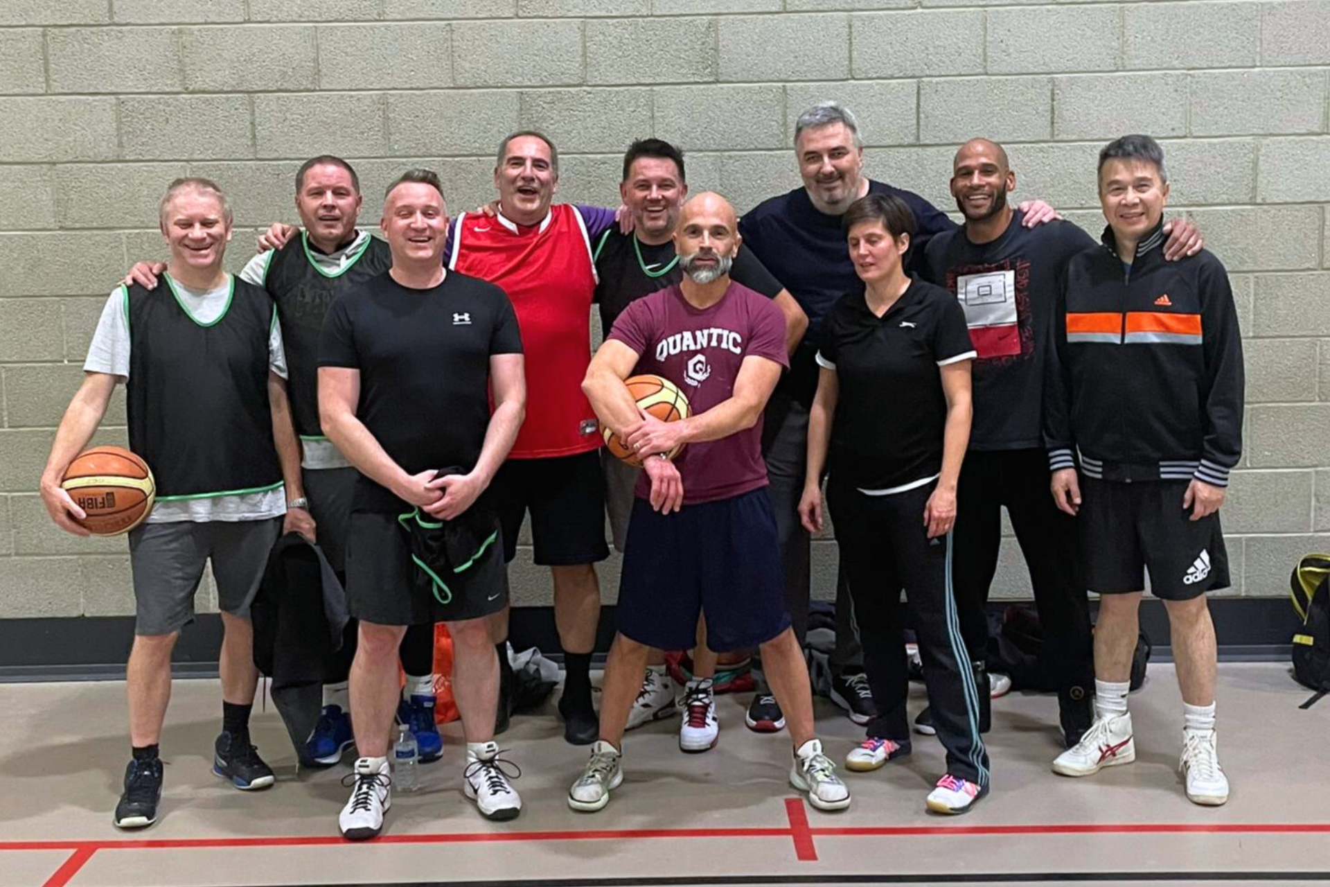 group of over forties standing in group smiling at camera on basketball court