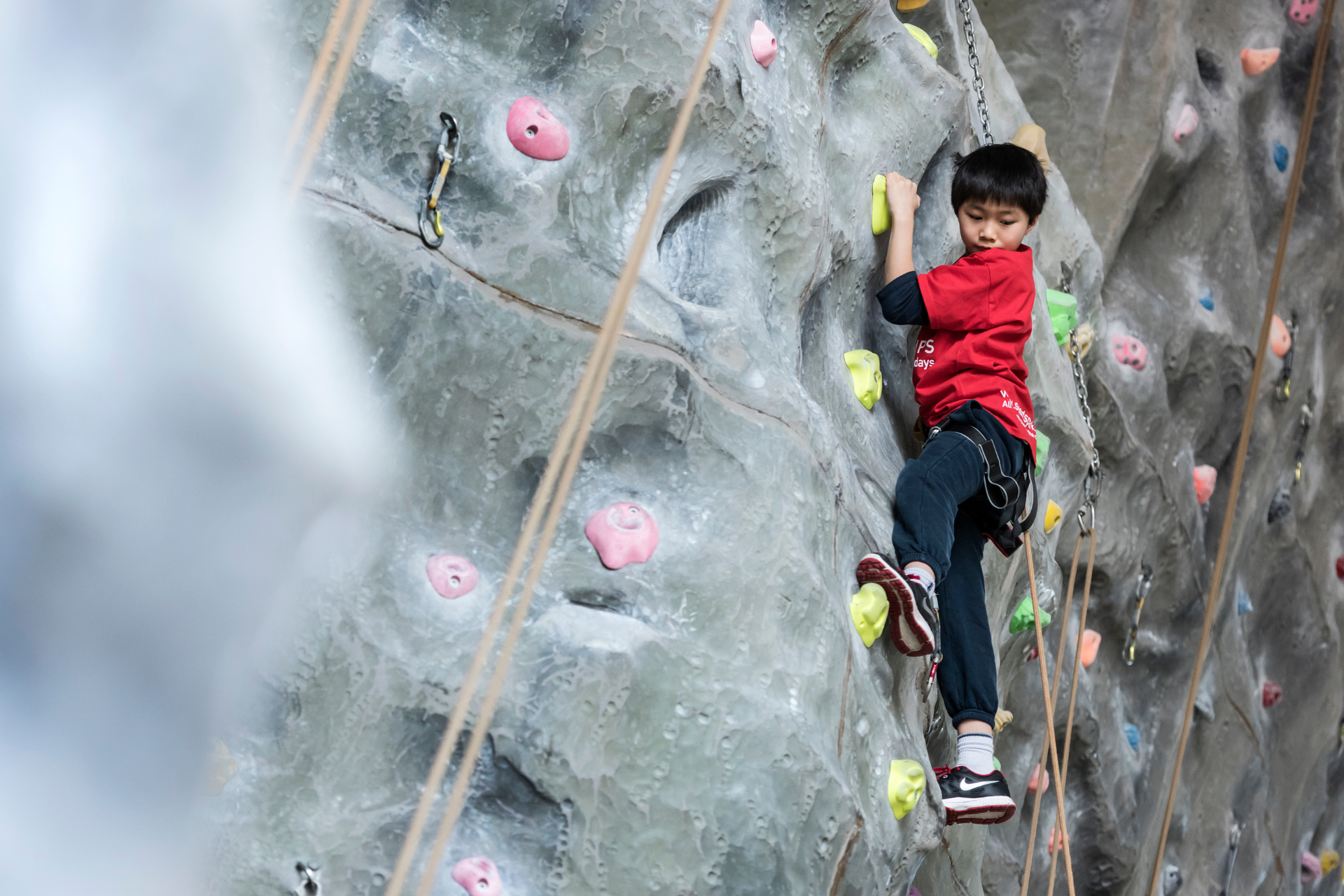 Boy on climbing wall looking down.