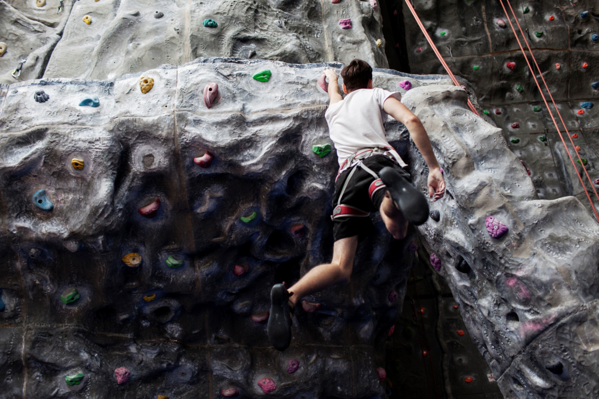 Boy hanging from climbing wall.