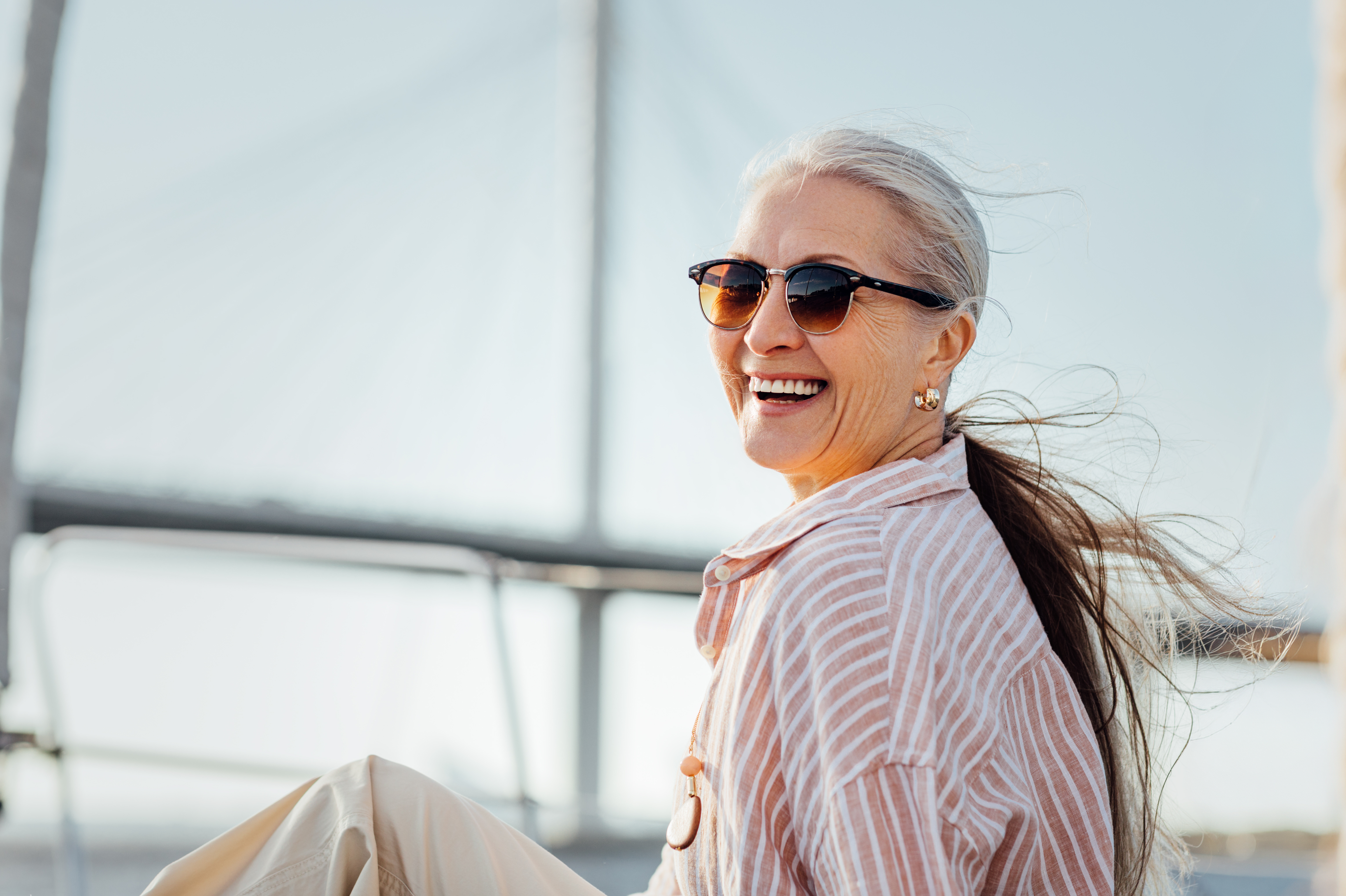 Ältere Dame mit Sonnenbrille an Bord lacht