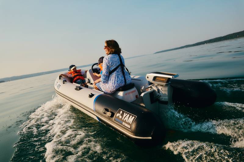 Woman driving an inflatable boat, powered by a Torqeedo Cruise 6.0 (48V) electric outboard built with recycled #tide® ocean-bound plastic