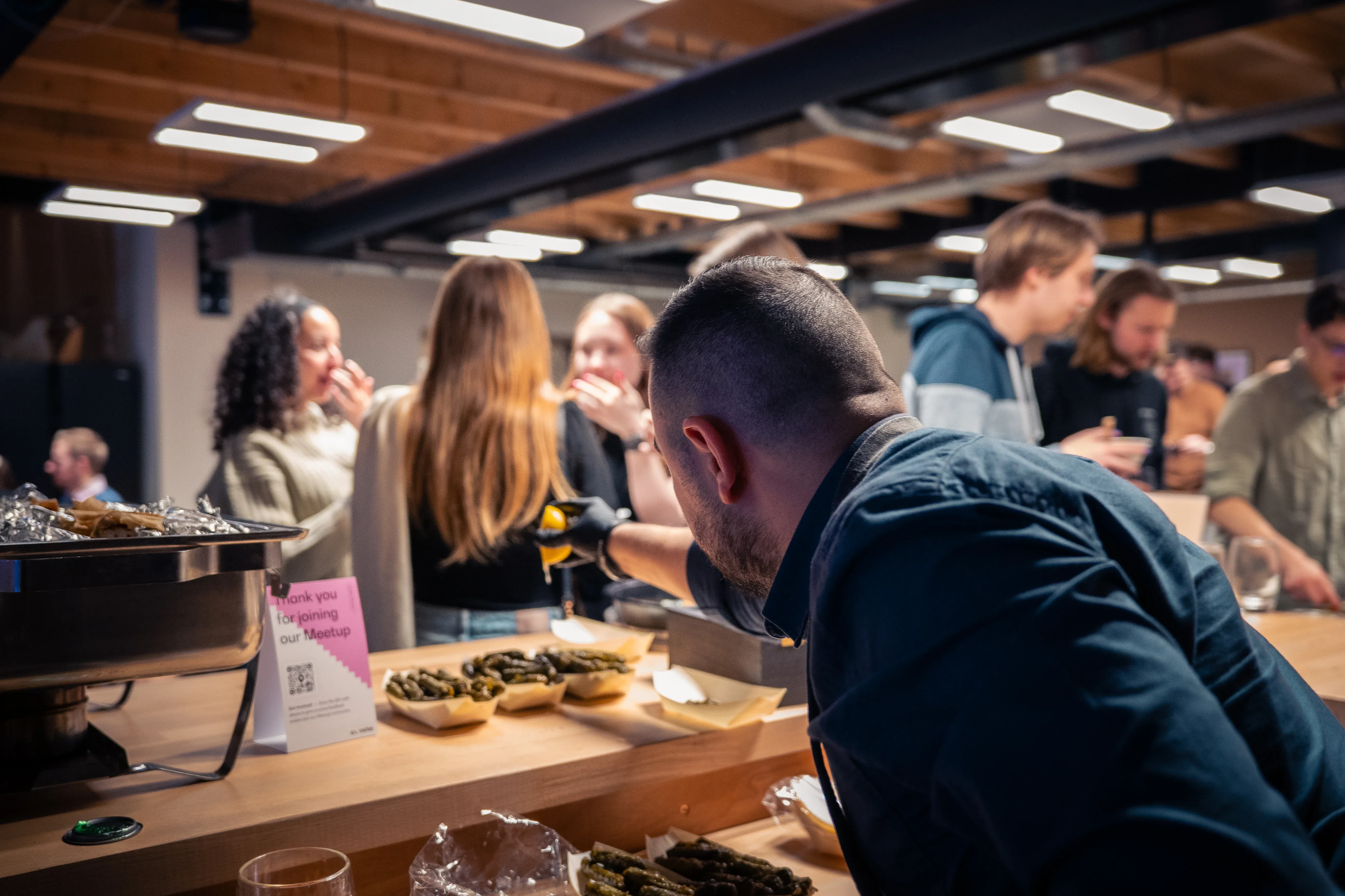 People socializing at the data science meetup, with a man in the foreground serving food.