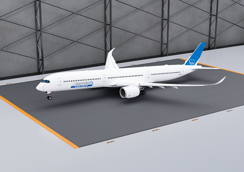 A white airplane with blue accents inside a wind channel with a textured metal wall.