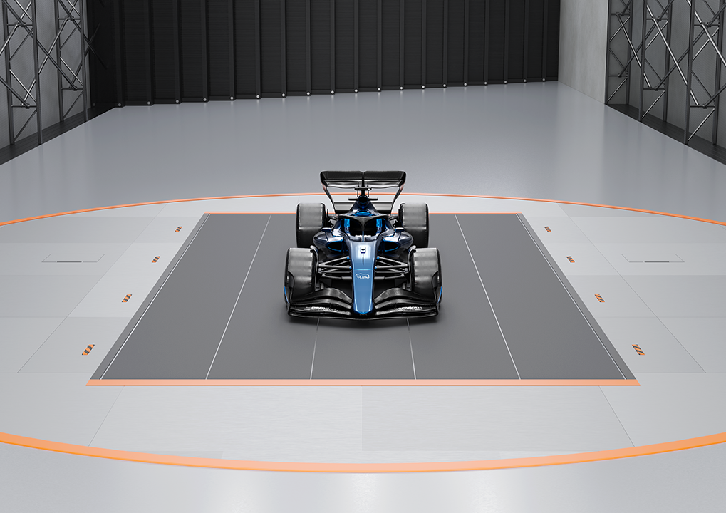 A sleek blue and black Formula 1 car displayed in a wind channel on a rotatable plattform with a gray floor and dark walls.