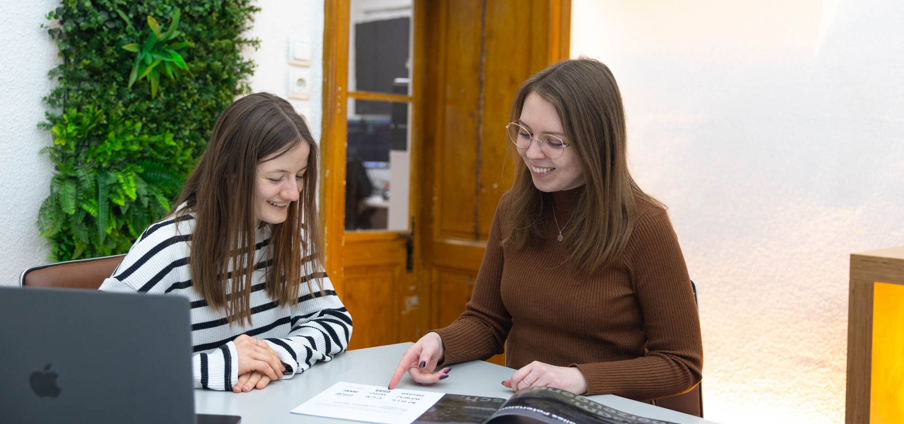 Unsere Grafikerinnen Julia und Jasmin schauen lächelnd auf unser Design Manual