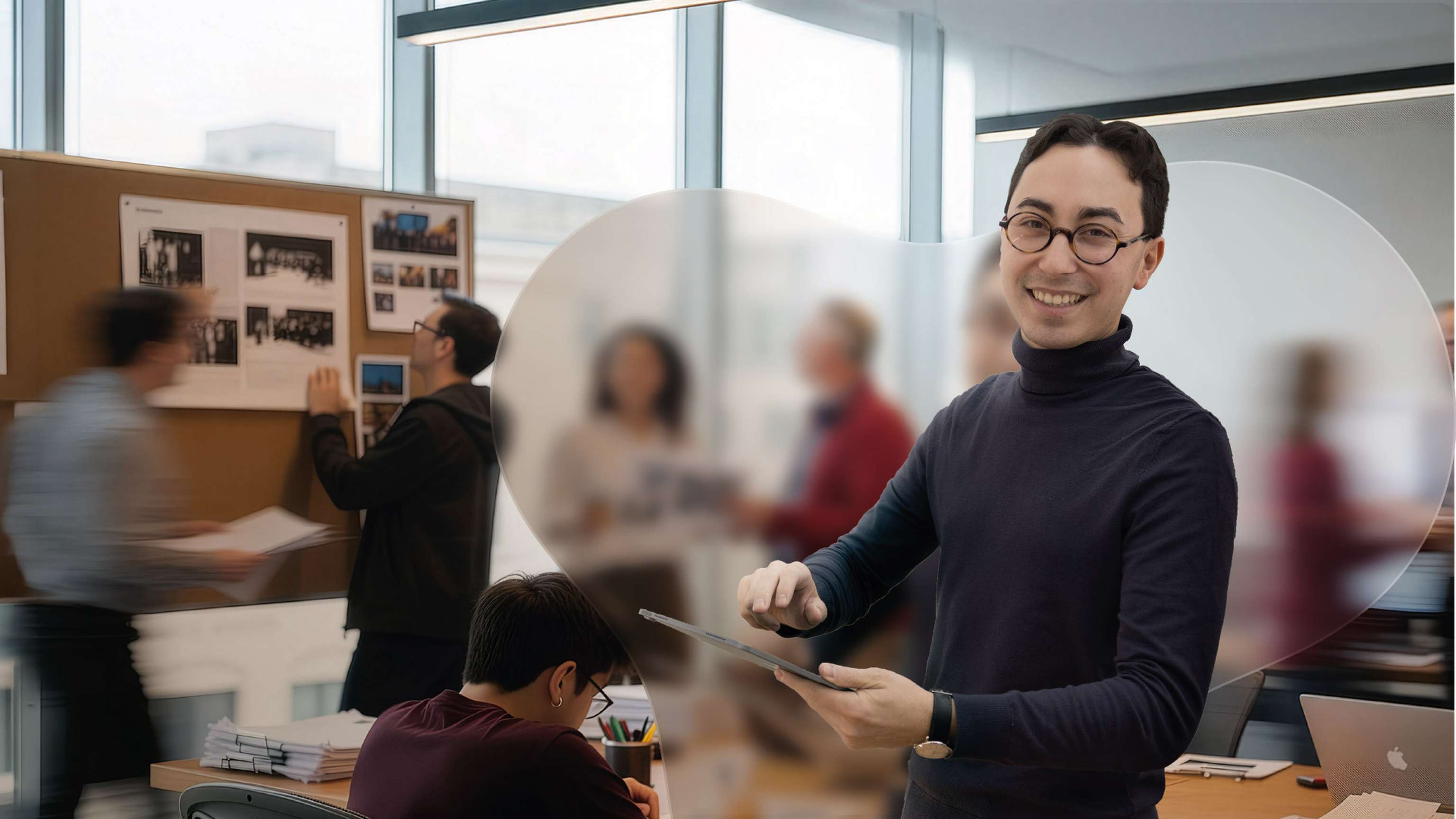 Das Bild zeigt eine geschäftige Redaktion im Hintergrund und einen lächelnden Redakteur im Vordergrund