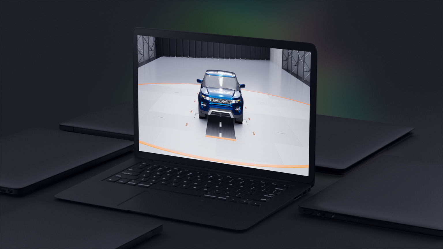 Laptop displaying a 3D model of a blue SUV in a virtual studio setting, surrounded by closed laptops on a dark surface.