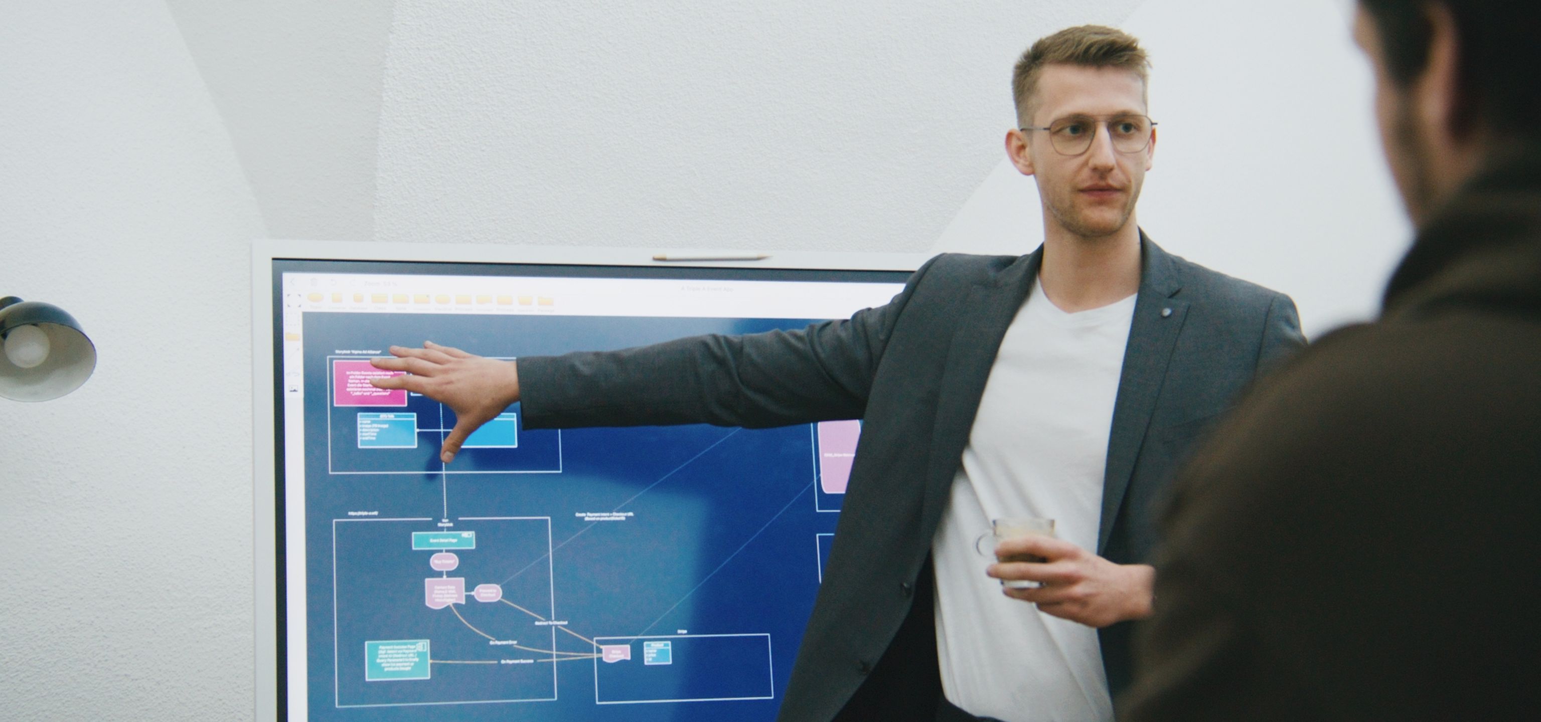Unser Head of Technical steht vor einem Bildschirm und erklärt Dinge