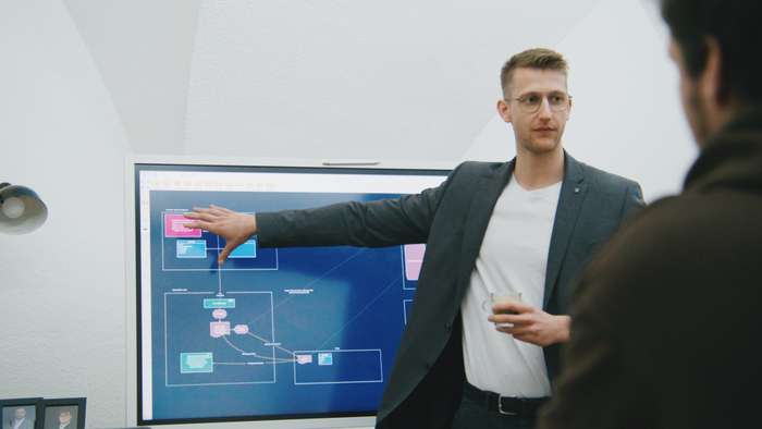 Unser Head of Technical steht vor einem Bildschirm und erklärt Dinge