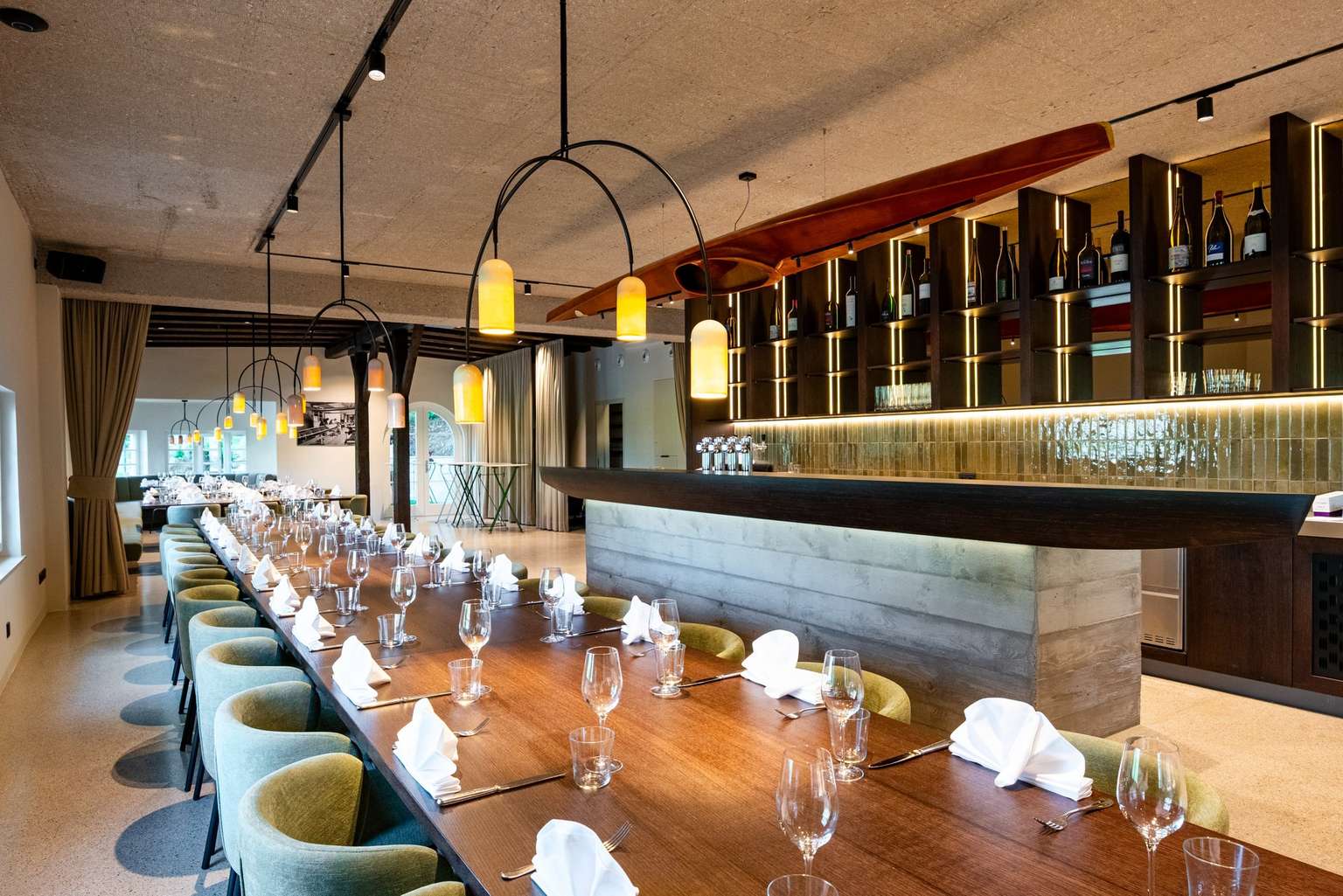 Eventlocation im Erdgeschoß des Paddlerhaus mit gedeckter Festtafel, Bar und Holzbalkendecke