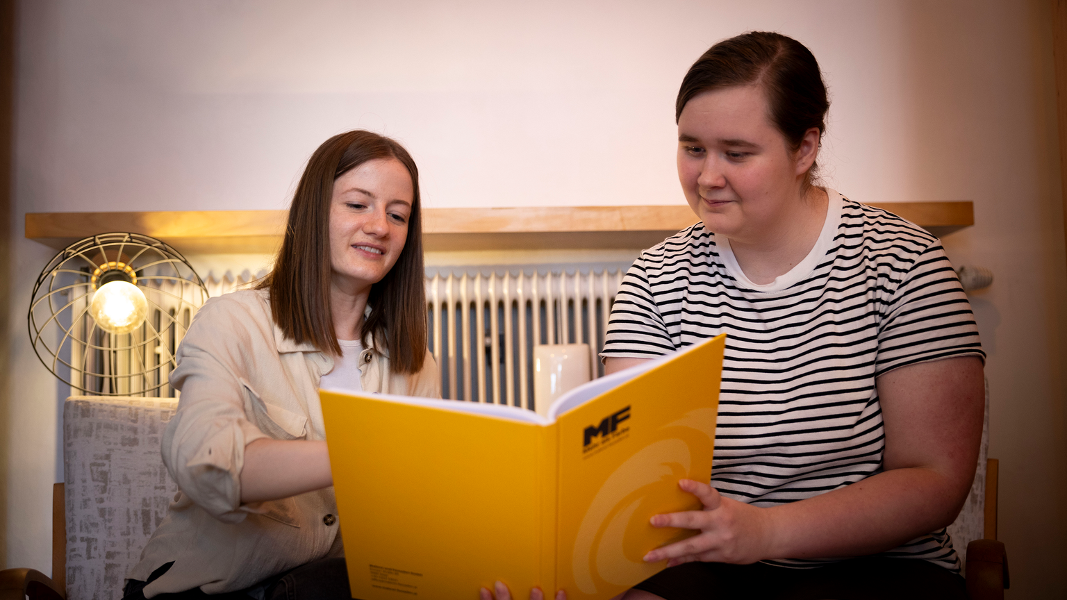 Zwei Personen lesen einen Produktkatalog.