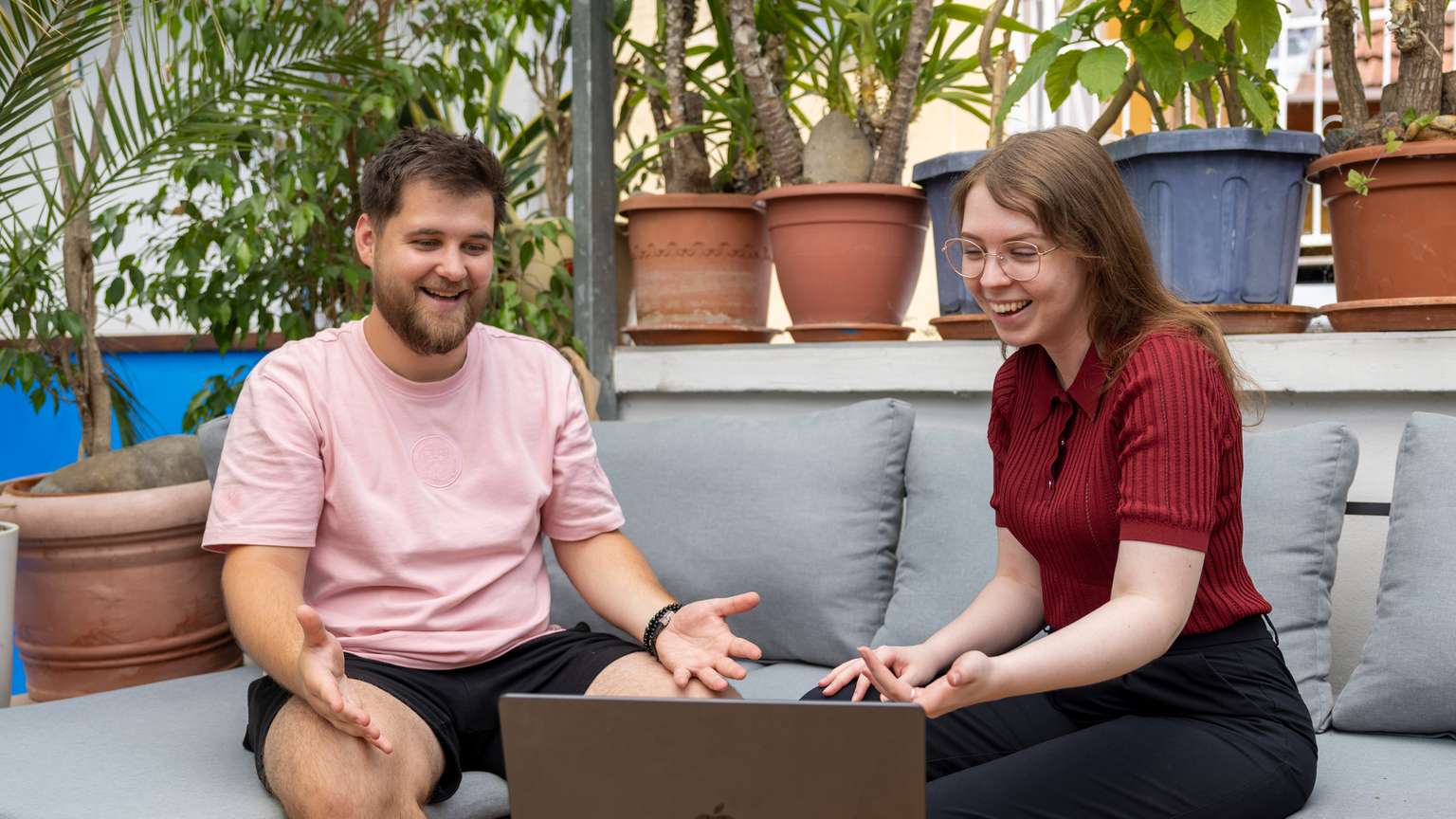 Zwei Personen, die mit glücklichen Gesichtern vor Laptop sitzen.