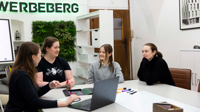 Eine Gruppe junger Leute sitzt an einem Tisch und reden angeregt.